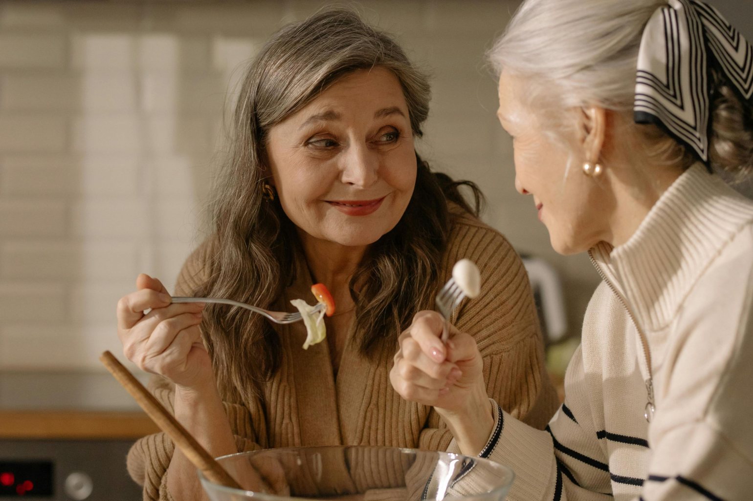 Two mature women eating healthy food and smiling